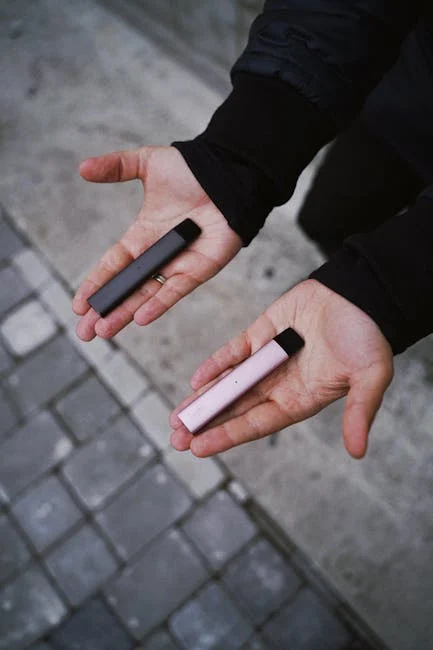 Osoba trzymająca mały e-papieros (Esin Vape 800 puffs) dyskretnie ukryty w dłoni w formalnym otoczeniu, np. podczas spotkania biznesowego.
